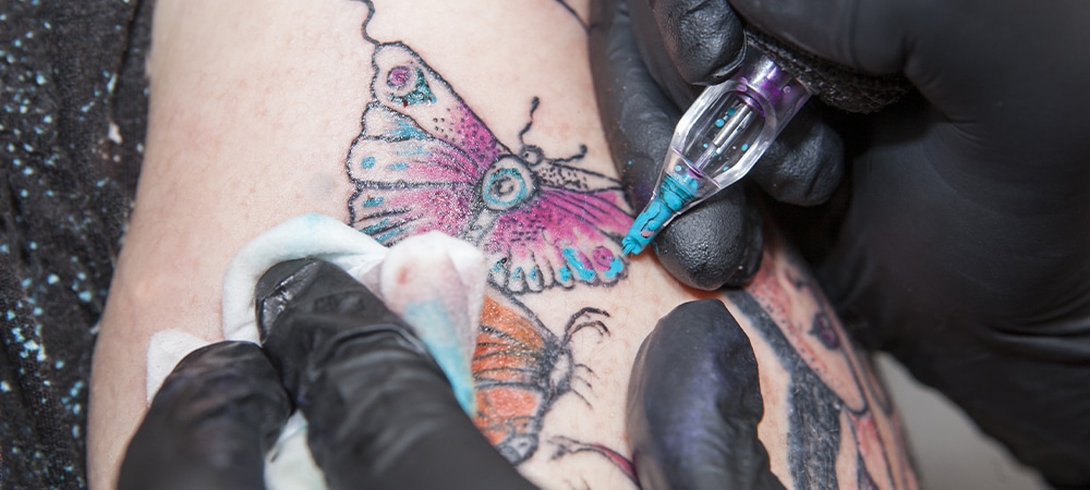 tattoo artist filling butterfly tattoo