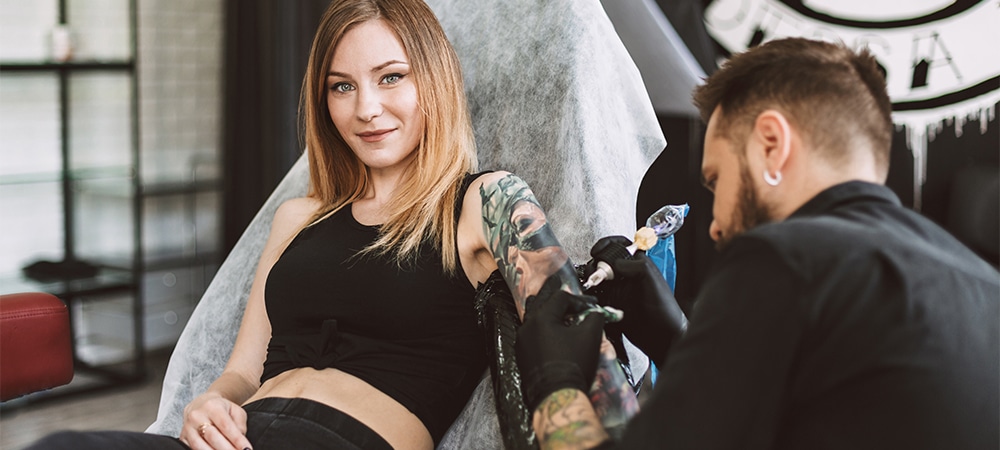 girl getting full sleeve tattoo in tattoo studio