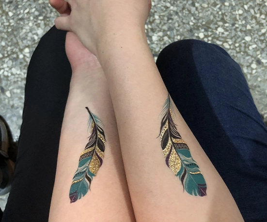 matching feather tattoos on forearm